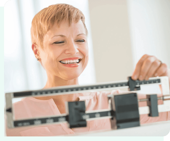 A woman is smiling while standing on a scale.