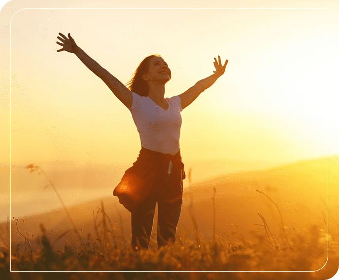 A woman standing in the grass with her arms outstretched.