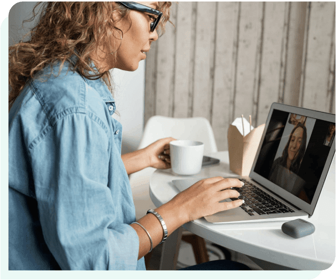 A woman sitting at a table using her laptop.