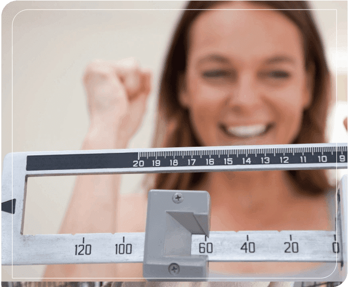 A woman is standing on the scale and smiling.