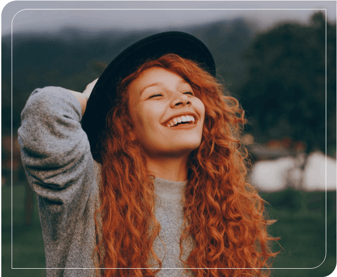 A woman with long red hair wearing a hat.