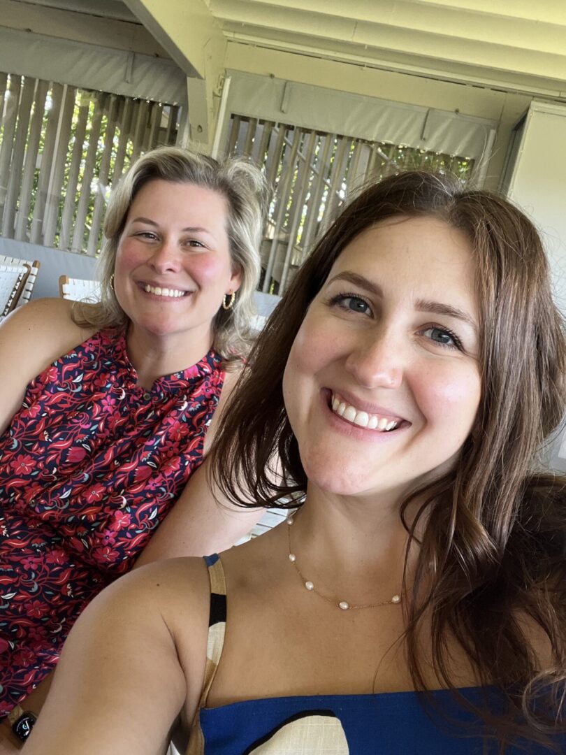 Two women smiling for a picture while sitting on the couch.