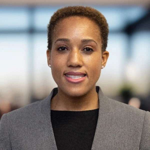 A woman with short hair wearing a gray jacket.